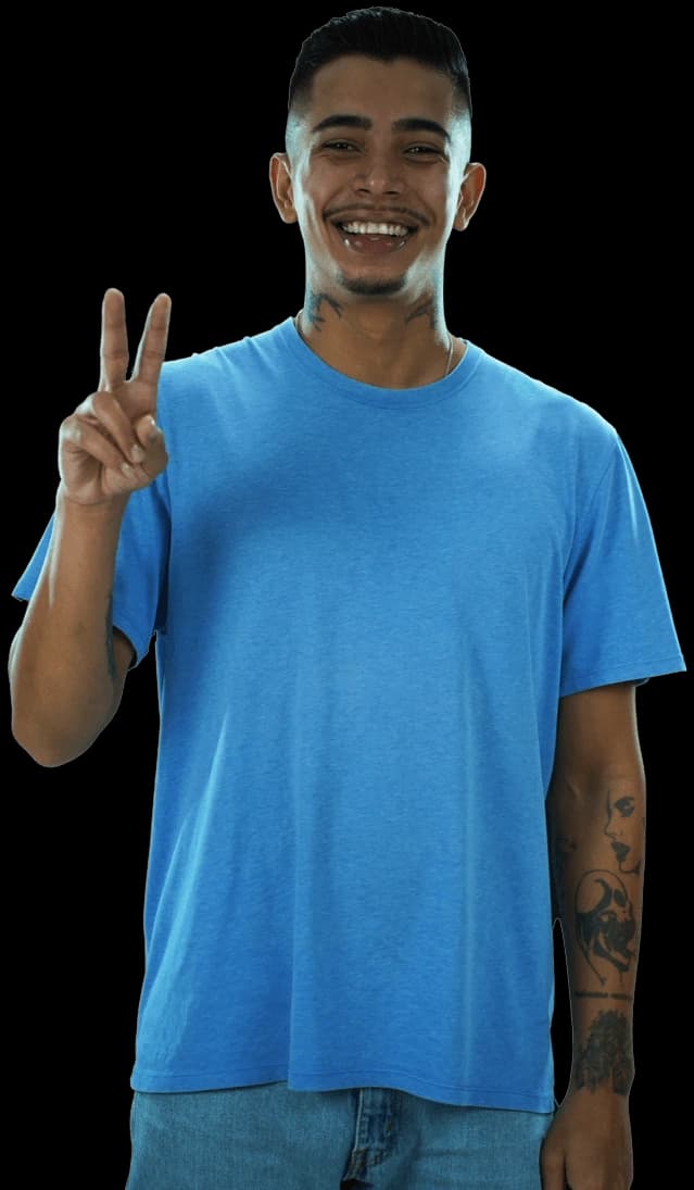 Fotografia de um rapaz sorridente vestindo uma camisa azul clara e fazendo o sinal de paz com a mão