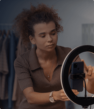 Criadora de conteúdo usando ring light e celular